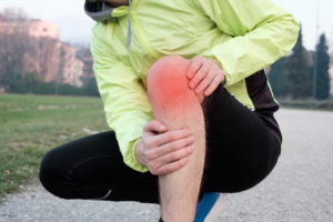 Runner with injured ankle while training in the city park in cold weather